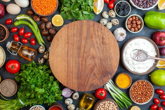 Top view round dough board beans in bowl garlic lemon tomato hazelnut pomegranate parsley on table