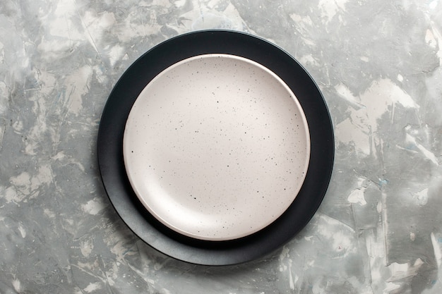 Top view of round empty plate black colored with white plate on grey surface