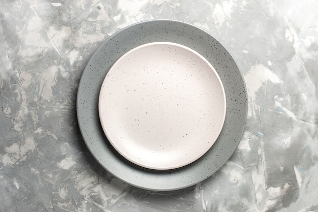 Вид сверху круглой пустой тарелки серого цвета с белой тарелкой на серой поверхности