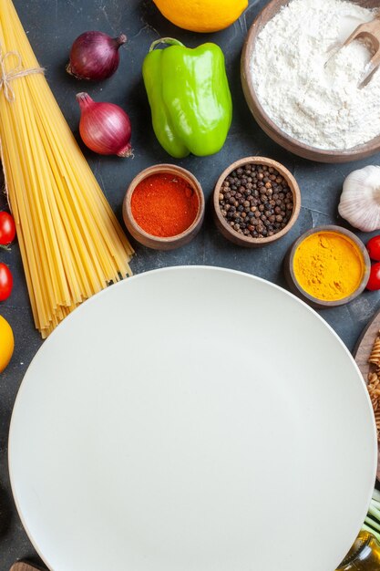 Top view round empty plate with raw pasta flour vegetables seasonings and eggs on the dark background food egg dough dinner meal fruit color