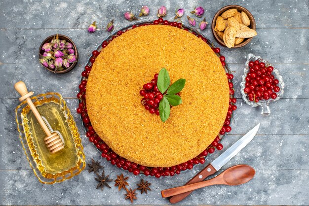 A top view round honey cake delicious and baked with red cranberries honey nuts on the grey desk cake biscuit sugar  photo