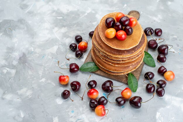 A top view round pancakes with cherries on the light desk cake fruit  color