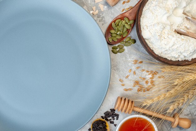 Top view round plate flour and honey bowls honey stick on table