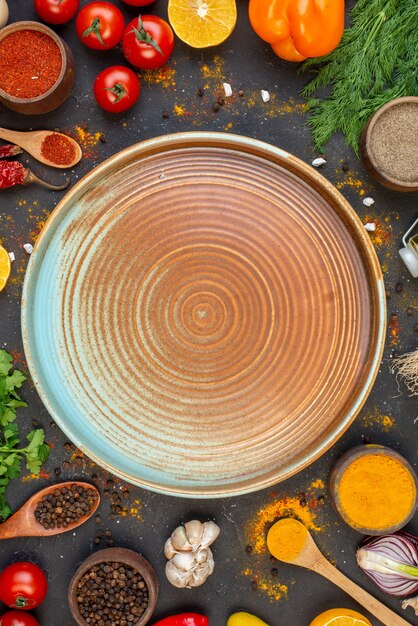 Top view round plate tomatoes black pepper in small bowl coriander dill on table