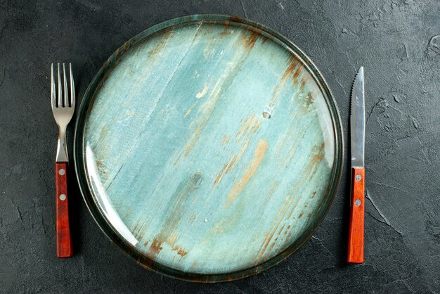 Top view round platter knife and a fork on dark surface