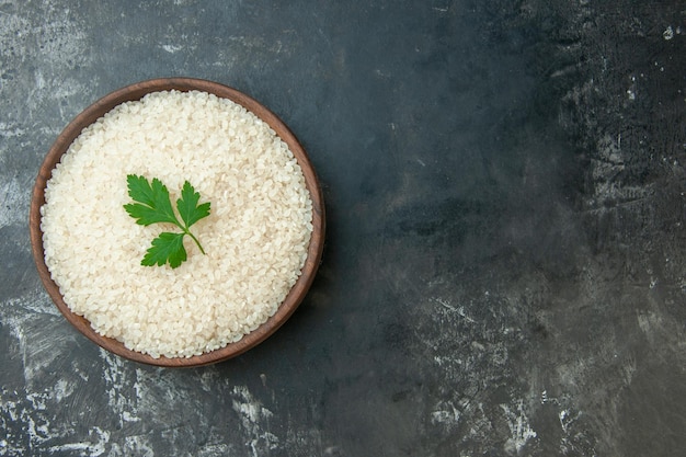 Top view of round rice in a brown bowl with green on the right side on gray background with free space