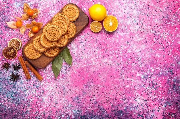 Вид сверху круглого сладкого печенья с корицей и лимоном на розовой поверхности