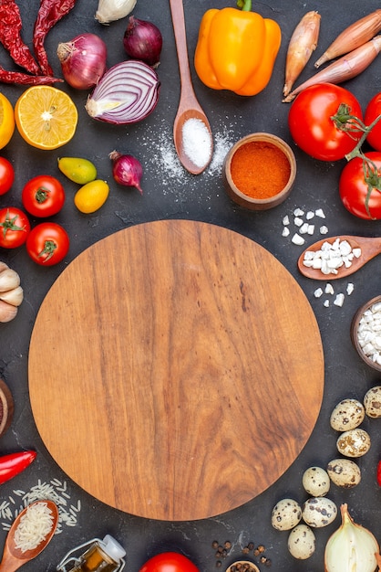 Free photo top view round wood board rice sea salt in wooden spoons tomatoes quail eggs on black table