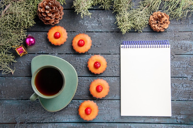 無料写真 上面図丸みを帯びた桜のカップケーキモミの木の枝クリスマスのおもちゃ松ぼっくりお茶のカップ暗い木製のテーブルの上のノート