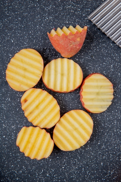 Foto gratuita vista dall'alto di fette di patate arruffate sul tagliere come superficie