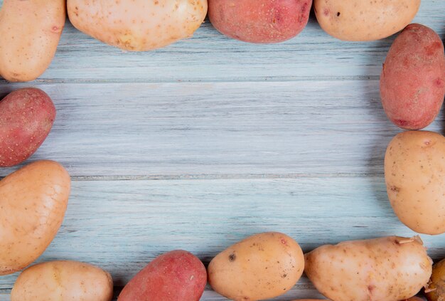 Top view of russet and red potatoes set in square shape on wooden surface with copy space