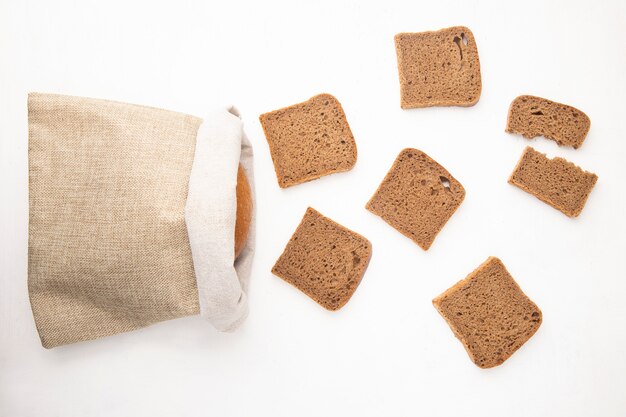 Top view of rye bread slices and sack with bread on white background with copy space