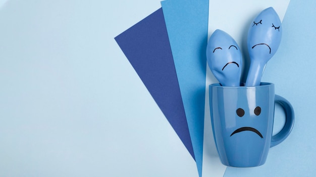 Top view of sad mug with frowny balloons for blue monday