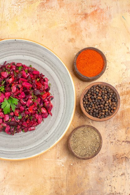 Top view salad on a ceramic plate with black pepper ground black pepper turmeric on a wooden background with copy place