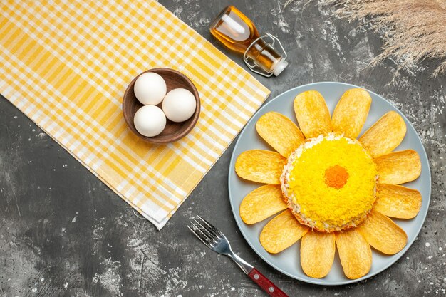 Free photo top view of salad on the right side with yellow napkin oil bottle fork wheat and bowl of eggs on side on dark grey table