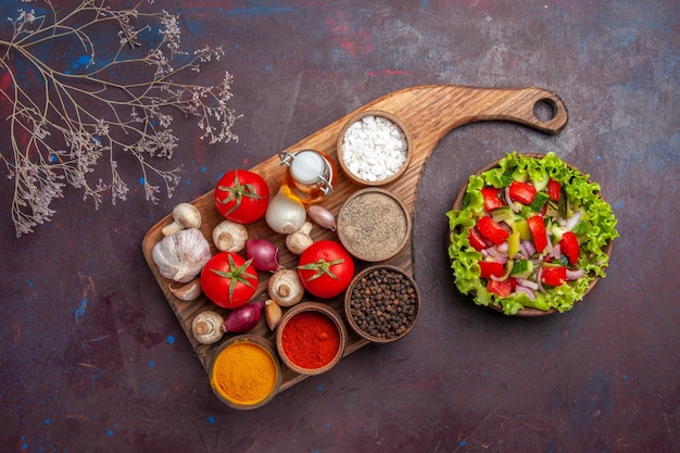 Vista dall'alto insalata e spezie spezie diverse pomodori funghi cipolle sul tagliere e insalata con verdure