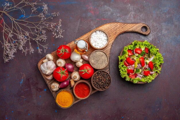 Top view salad and spices different spices tomatoes mushrooms onions on the cutting board and salad with vegetables