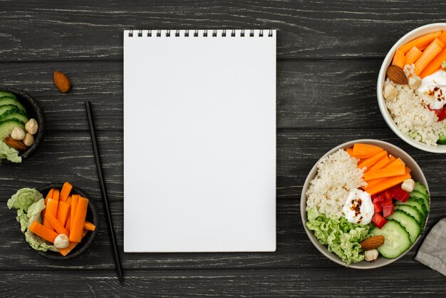 Top view salad with couscous and blank notepad