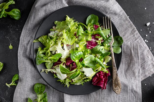 Top view salad with different ingredients on dark plate