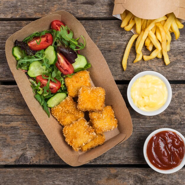 Top view of salad with french fries and fried chicken