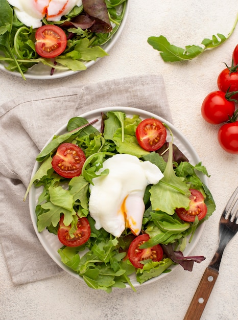 Top view salad with tomatoes and fried egg with fork