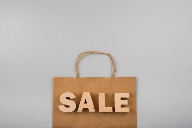 Top view of sale letters with paper bag on plain background