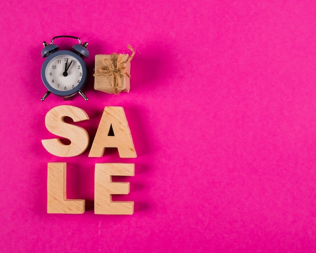 Top view of sale word and clock on pink background