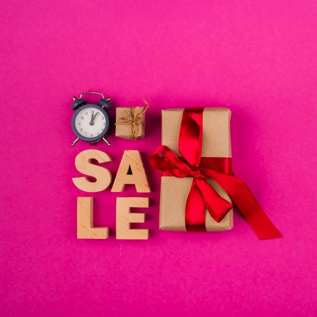Top view of sale word and presents with pink background