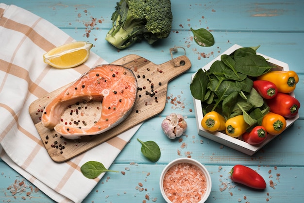 Free photo top view salmon steak on wooden board with ingredients