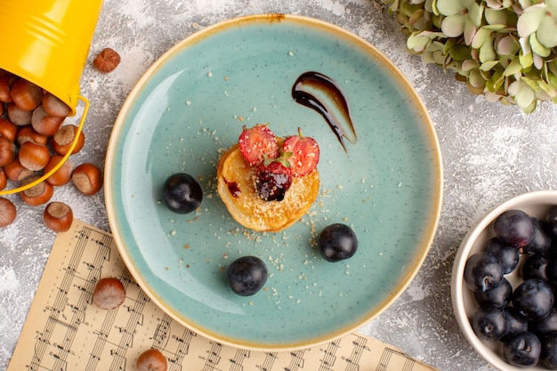 Top view salted chips designed with strawberries inside plate along with blackthorns on the white table, chips snack fruit berry