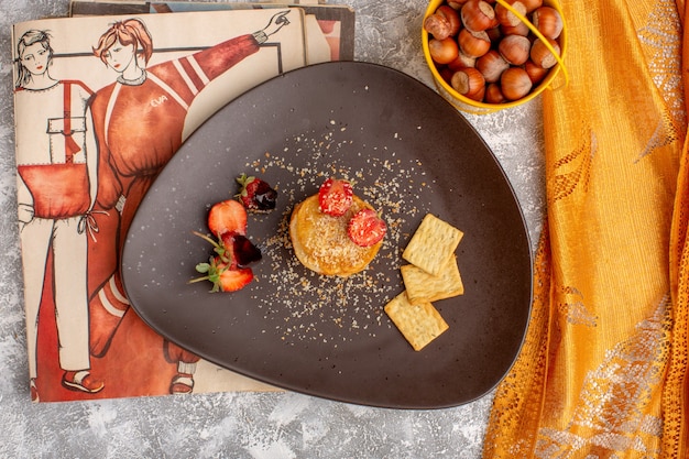 Вид сверху соленые чипсы с клубникой внутри тарелки на белом столе, чипсы, закуска, фруктовые ягоды
