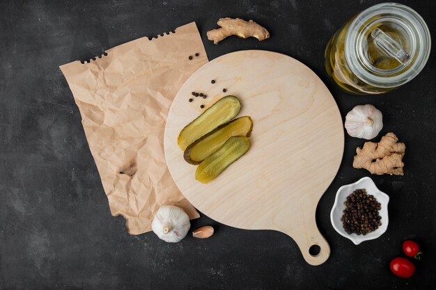 Top view of salted cucumbers and ginger garlic pepper space on black background with copy space