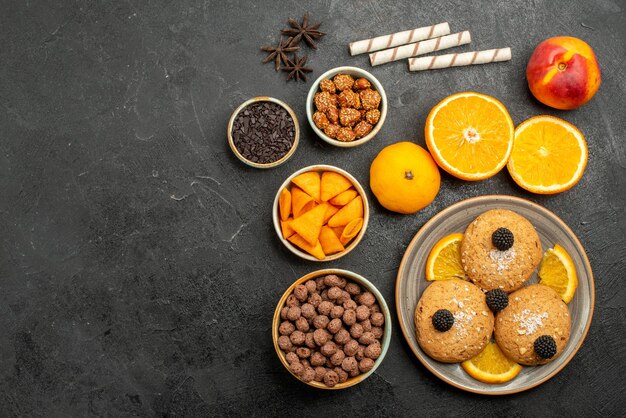 짙은 회색 표면의 달콤한 과일 비스킷 쿠키 차에 오렌지 조각이 있는 탑 뷰 샌드 쿠키