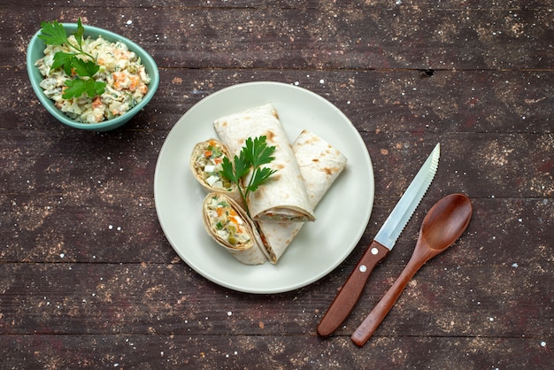 갈색 나무 책상 스낵 식품 식사 샌드위치에 mayyonaise 샐러드 흰색 접시와 함께 내부 샐러드와 고기로 슬라이스 상위 뷰 샌드위치 롤