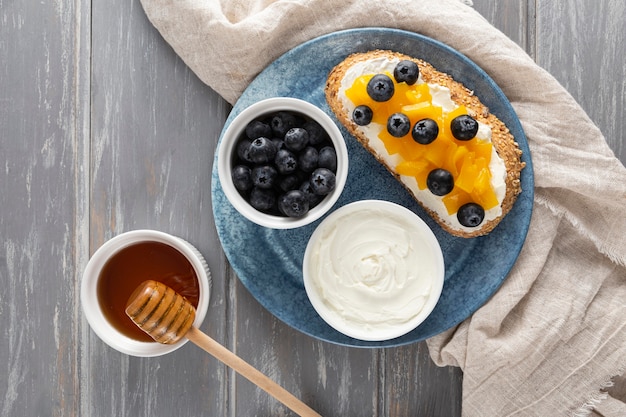 Top view sandwich  with cream cheese and fruits on plate with honey