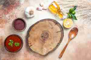 Free photo top view sauce wooden board lemon bottle of oil sauce spices spoon