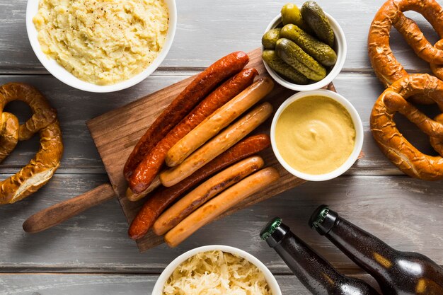 Top view of sausages with pretzels with beer bottles