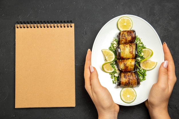 Vista dall'alto involtini salati di melanzane piatto cucinato con fette di limone sulla superficie scura piatto da cucina con olio per cena dinner