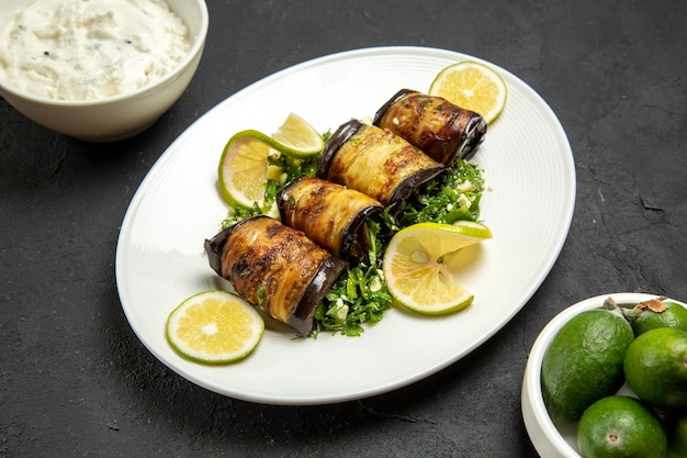 Top view savory eggplant rolls cooked dish with lemon slices and feijoa on the dark surface dinner oil meal dish cooking food