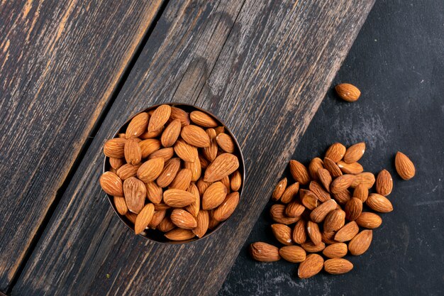 Top view scattered almond on wooden and black stone table. horizontal