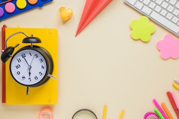 Top view of school supplies and alarm clock