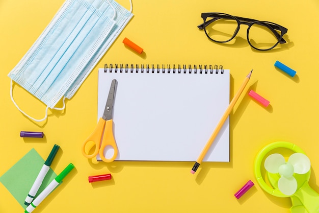 Top view of school supplies with glasses and notebook