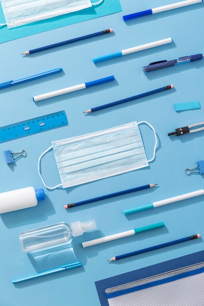 Top view of school supplies with loads of pencils and face mask