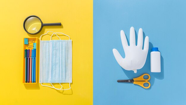 Top view of school supplies with medical mask and scissors