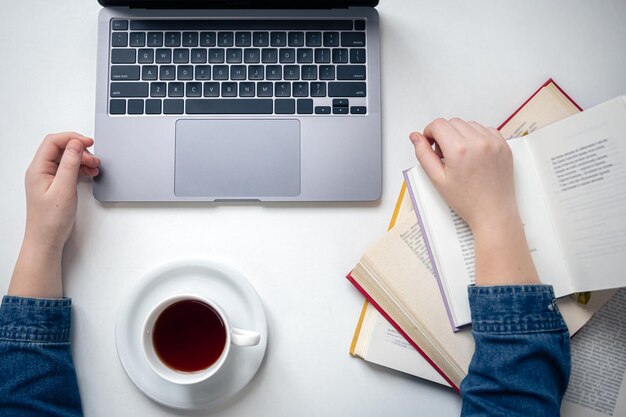 Top view schoolboy desktop laptop books and tea cup