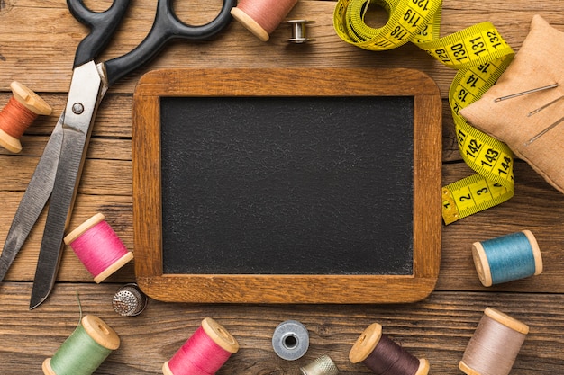 Free photo top view of scissors with measuring tape and chalkboard