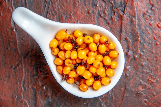 Free photo top view sea buckthorn in white bowl on dark red table