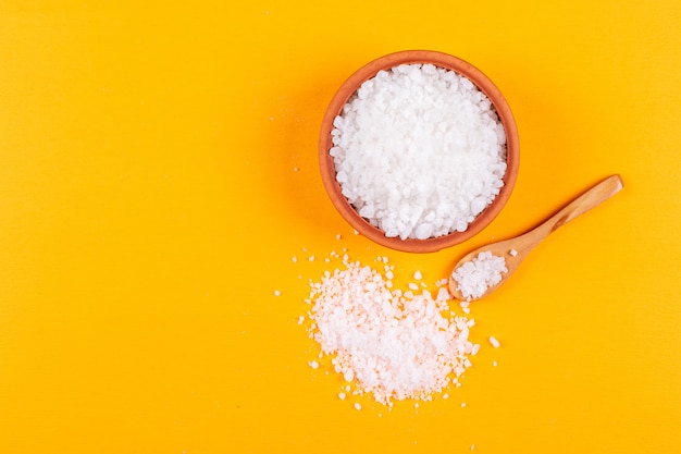 Top view of sea salt in wooden spoons, bowl and nearby