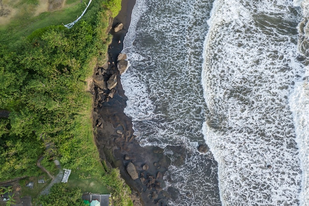Вид сверху на море с волнами, разбивающимися о скалы