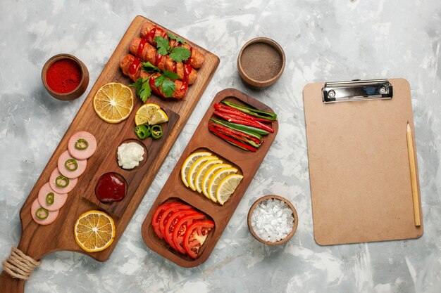 Top view seasonings and vegetables with lemon and sausages on white desk